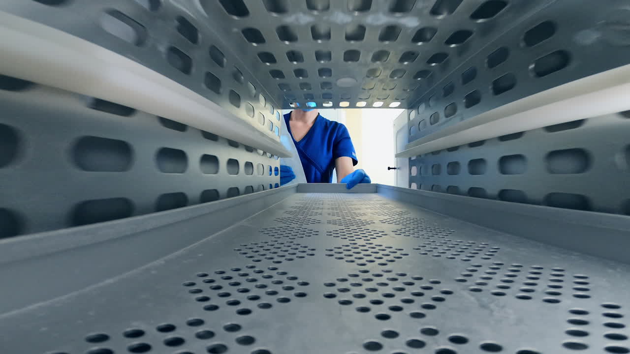 The inside of the sterilization machine. Nurse opens the doors and places a bag with a tool into equipment and closes the door.