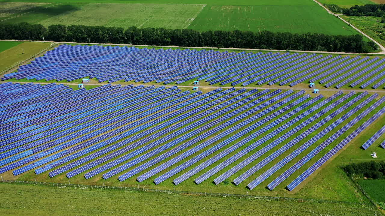 Solar battery panel on the green meadow. Flight over long solar panels on field. Alternative green energy. Aerial view