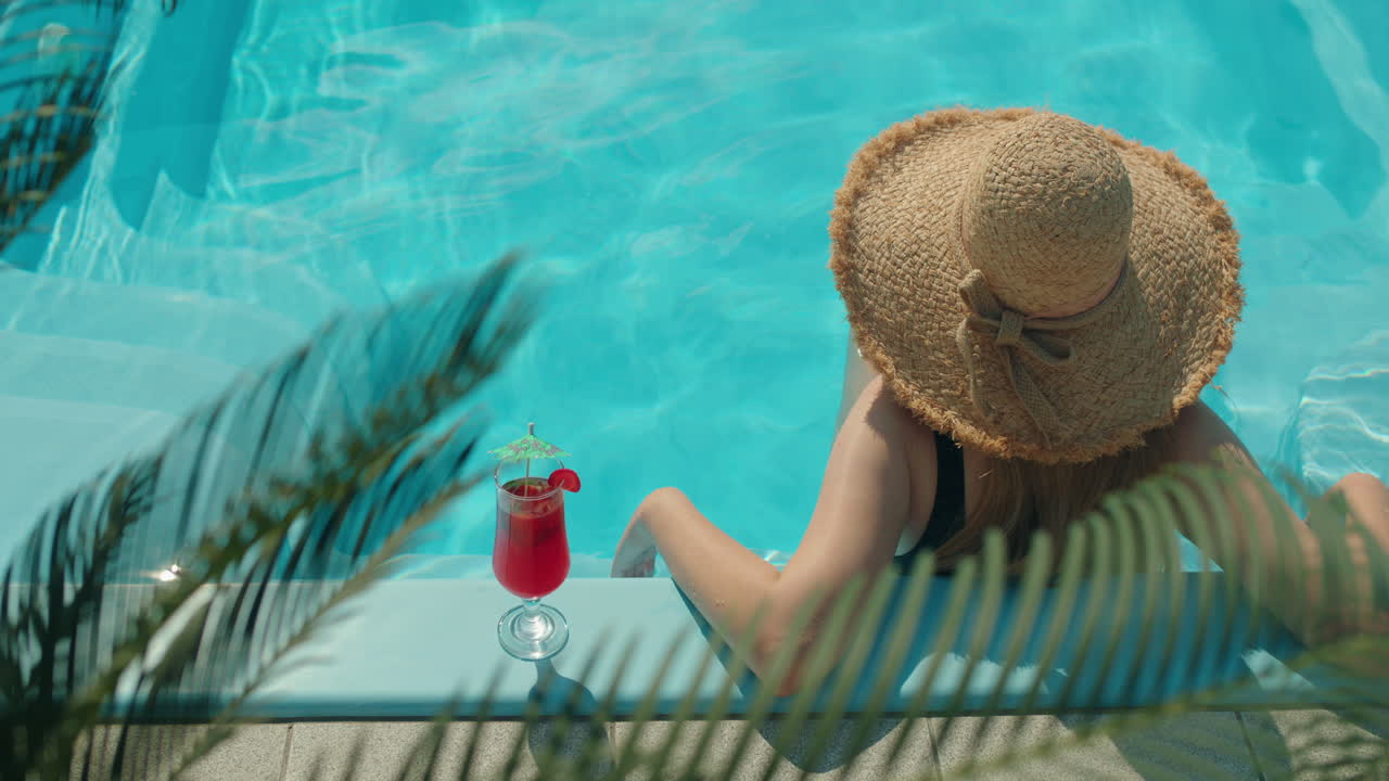Woman Relaxing in a Swimming Pool with a Cocktail