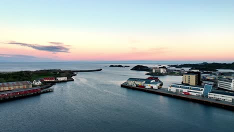 midnight sun aerial of svolvaer port with marina, breakwater and glowing horizon over the sea