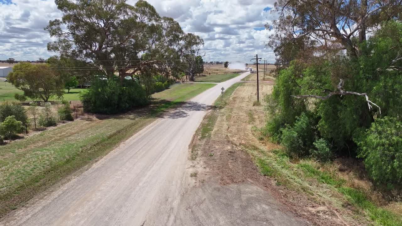 Rise up over dusty country road to reveal a large truck crossing a canal