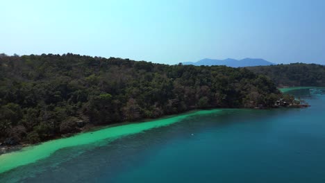 tropical island landscape with turquoise waters and dense forest beach cottage on koh wai island in thailand. unbelievable aerial view flight static tripod hovering drone