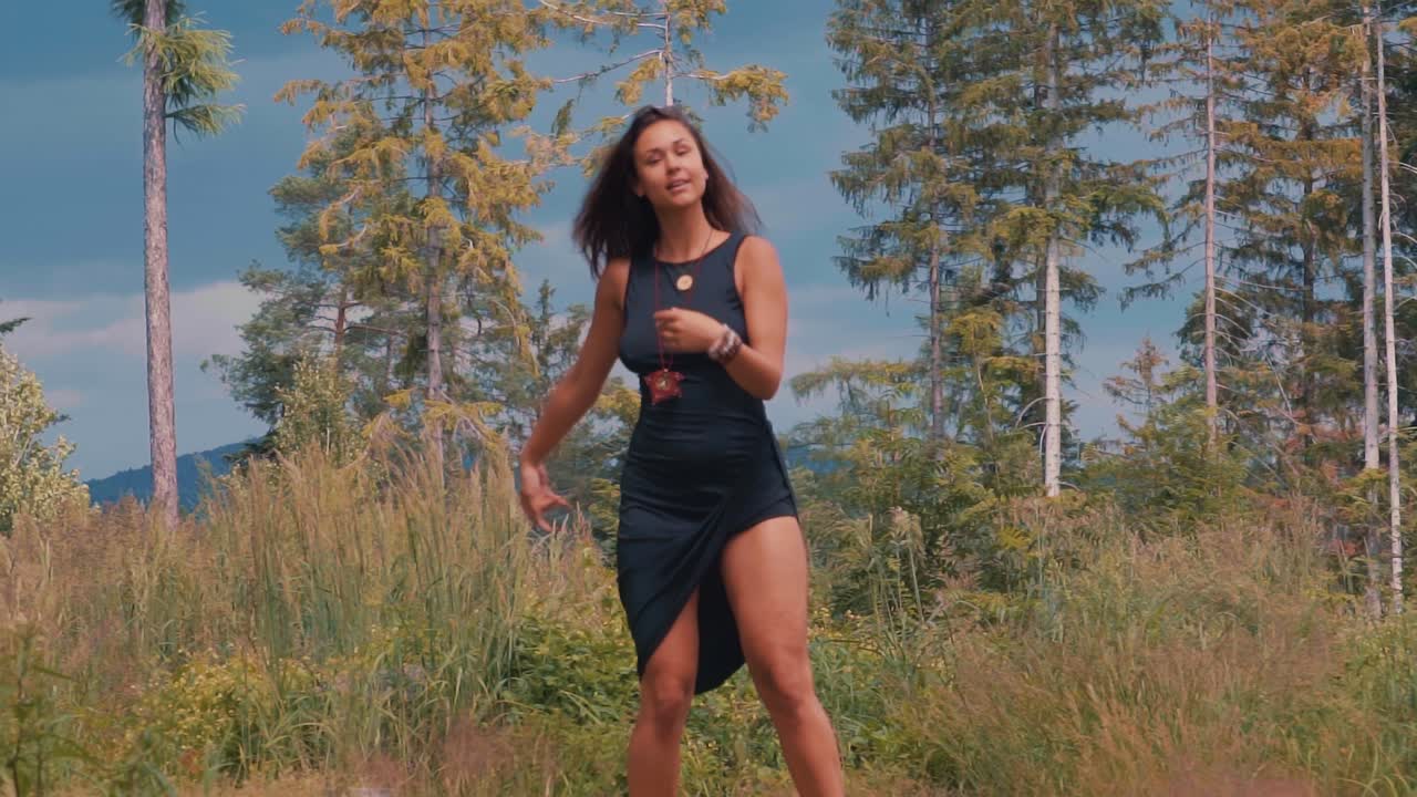 Mørkhåret boheme-kvinde danser som fri ånd i skoven i ét med naturen