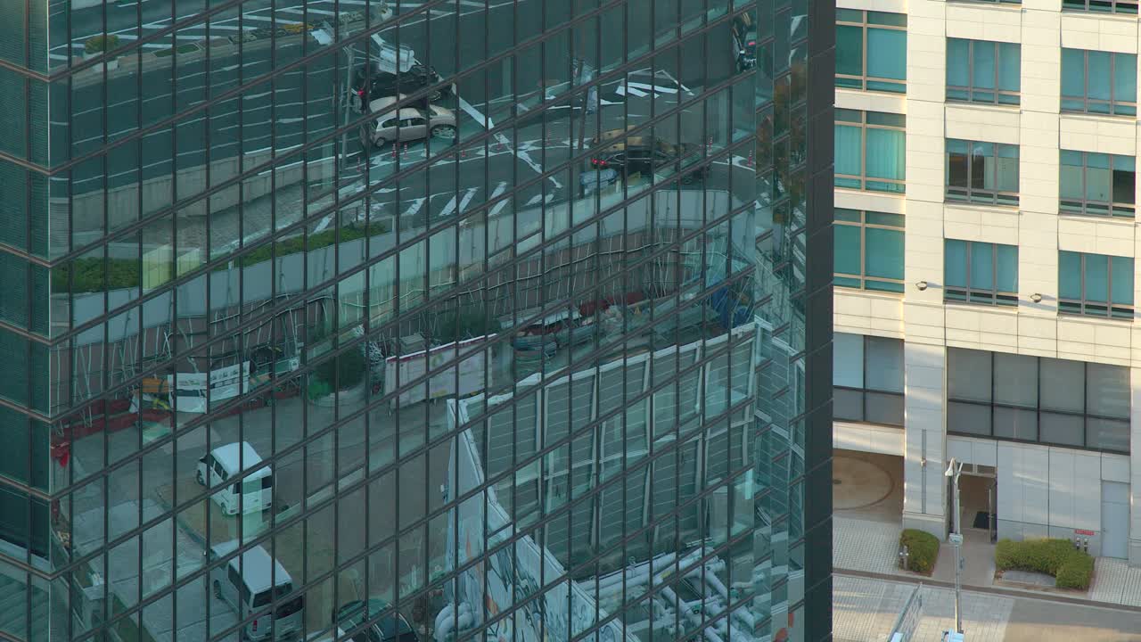 La calle de la ciudad se refleja en las ventanas de cristal color verde azulado de un edificio de gran altura