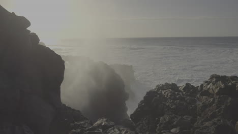 ocean waves crashing on volcanic rocks at sunset