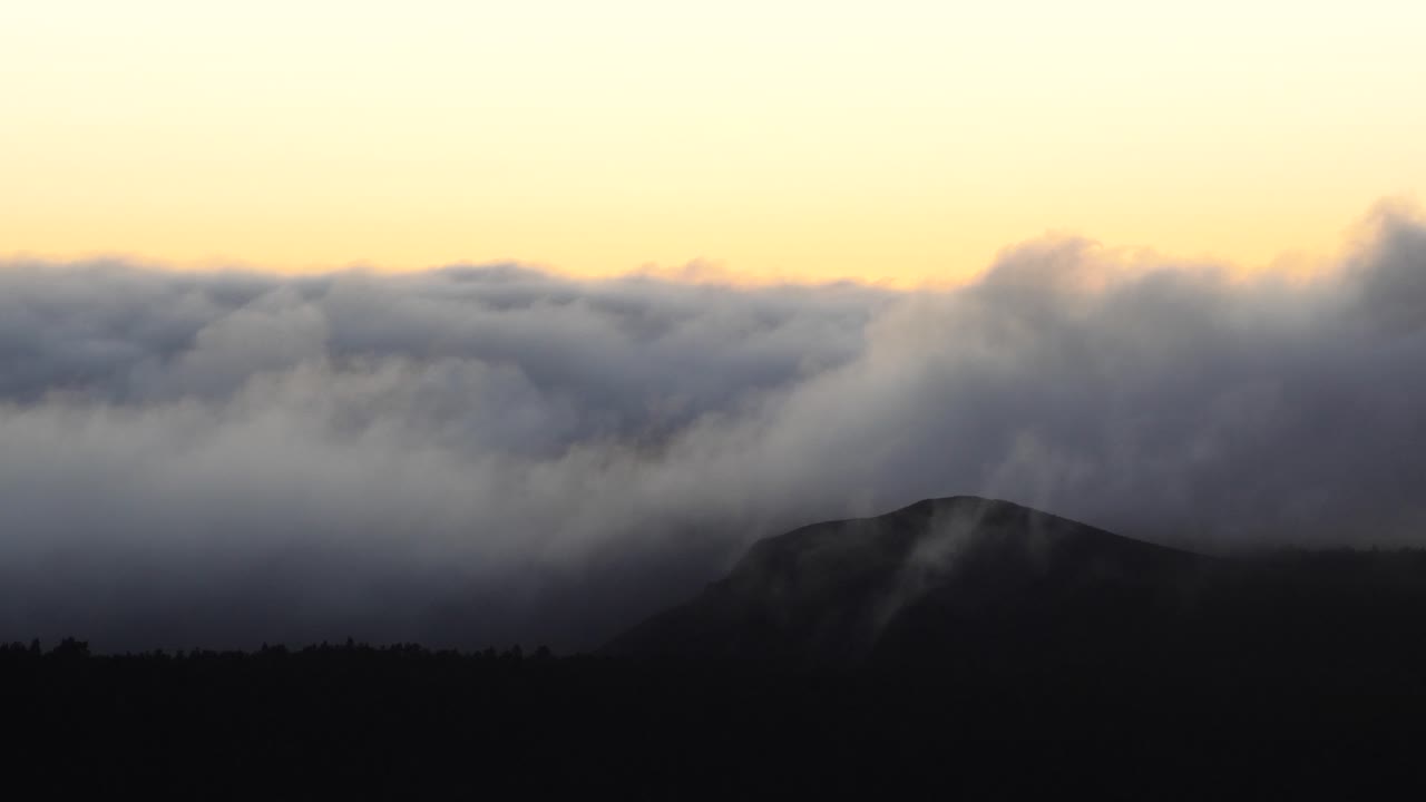 espesas nubes caen de las montañas durante el amanecer