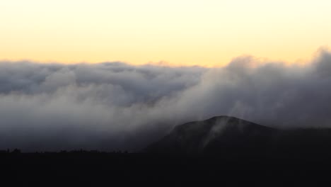 nuvens grossas rolam montanhas durante o nascer do sol