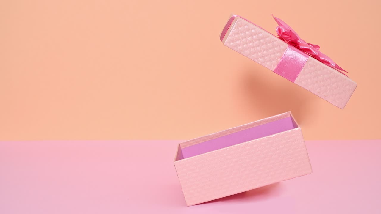 Regalo creativo romantico rosa pastello con nastro che si apre su tema rosa acceso e arancione. Stop motion.