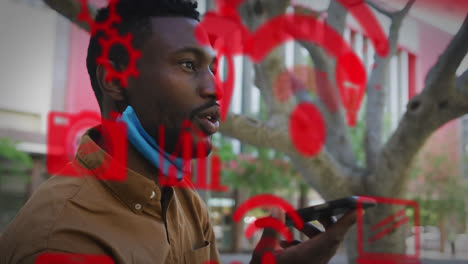 múltiples iconos digitales contra un hombre afroamericano con la máscara bajada hablando en el teléfono inteligente
