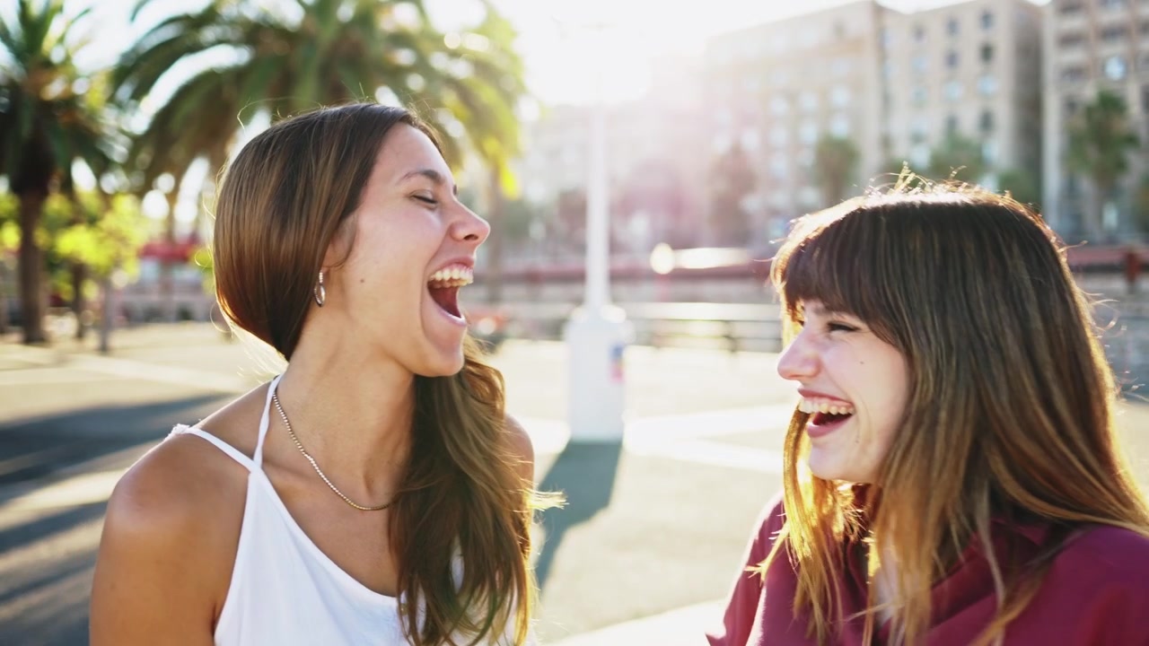 Due giovani donne felici che parlano e ridono all'aperto.