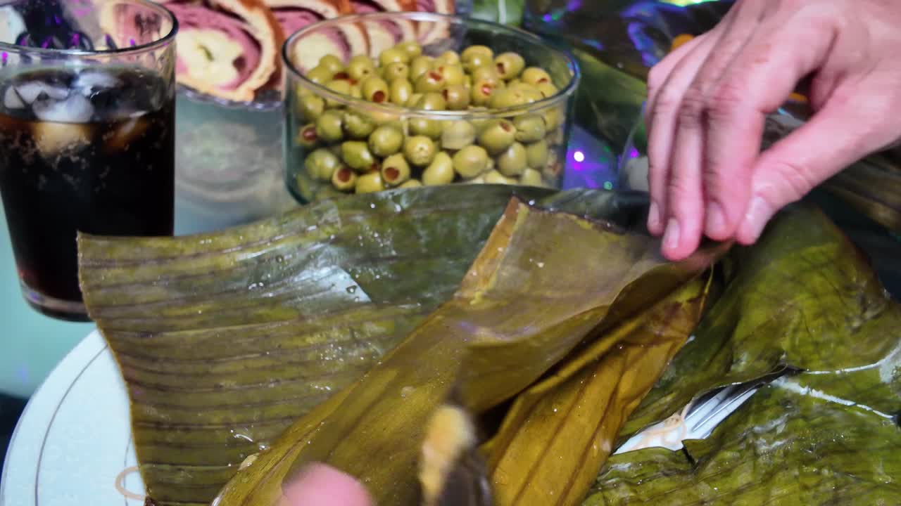 Yemek masasında muz yapraklarından hallaca (özellikle tatil sezonunda hazırlanan geleneksel Venezuela yemeği) saran ellerin yakın çekimi. Şenlikli bir yemeği paylaşma ritüeli