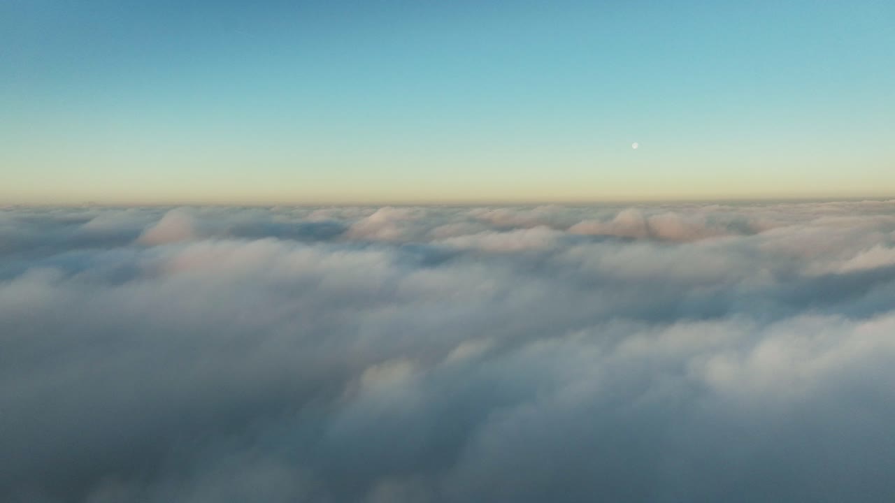 Sidewards descent through white puffy clouds - airplane view at sunset