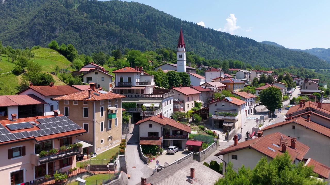 Slovenya'daki Most na Soci kasabasının havadan drone görüntüsü, yerleşimi, çevredeki tepeleri ve kırsal manzarayı gösteriyor