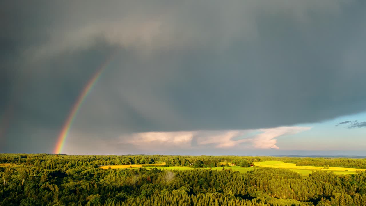 Beautiful rainbow in aerial hyperlapse with moving storm clouds.