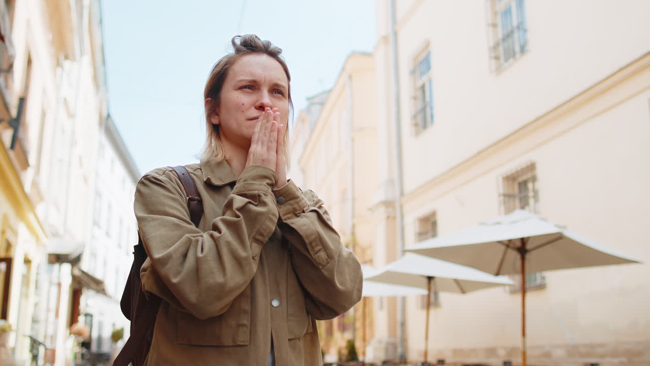 Woman praying with closed eyes to god asking for blessing help forgiveness outdoors on city street