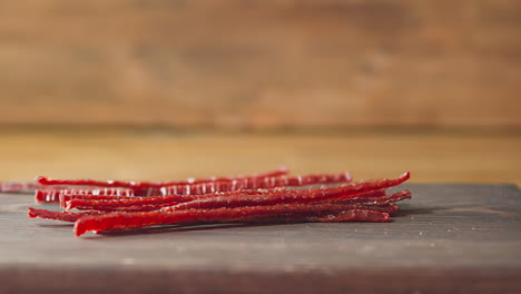 Sabrosos-Palitos-De-Salmón-Secados-Al-Sol-Caen-Sobre-Una-Tabla-De-Madera