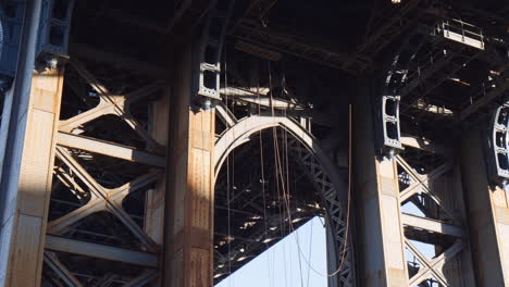 rusted steel beams and hanging ropes underneath manhattan bridge, low angle