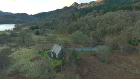 Drone-dolley-shot-over-Trossachs-church-in-autumn-colored-nature