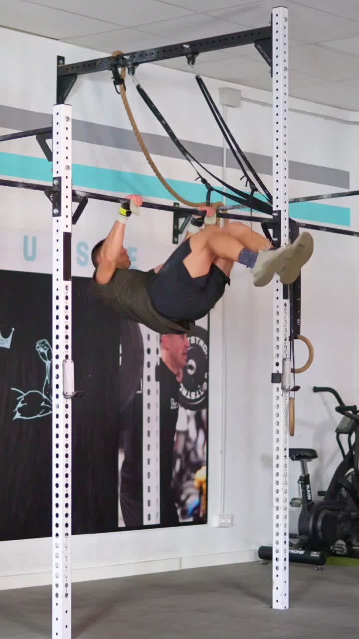 Determined Man Performing Muscle-Up Exercise on Pull-Up Bar in Gym