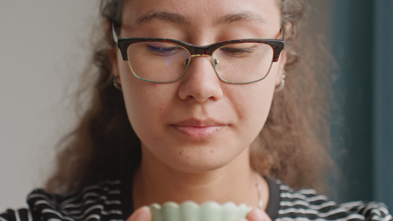 Hotel guest inhaling cup aroma, grounded. Soft window light, steady gaze upward, glasses reflection, subtle smile, morning routine in hotel suite, slow breath, planning day ahead with calm confidence