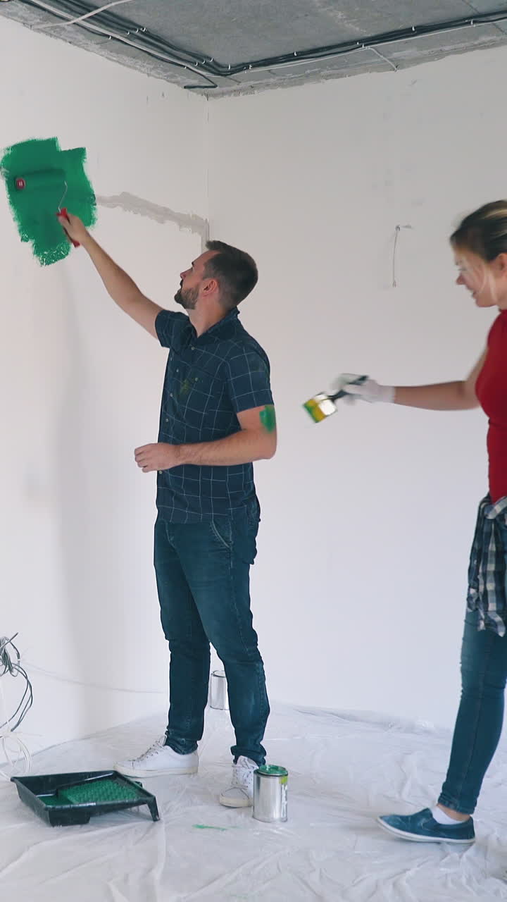 positive family of bearded man and happy blonde girl paint each other having fun near white wall in empty spacious room