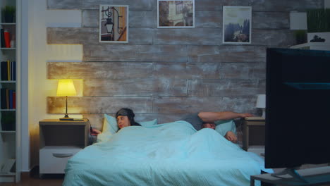 young couple under the sheets in their bedroom