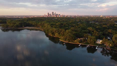 drone push in towards skyline of minneapolis from cedar lake during a summer sunset 4k