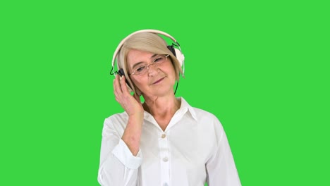 mujer mayor tranquila escuchando música con auriculares en una pantalla verde, tecla de croma