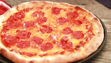mano colocando pizza de pepperoni caliente en la superficie de la mesa de madera