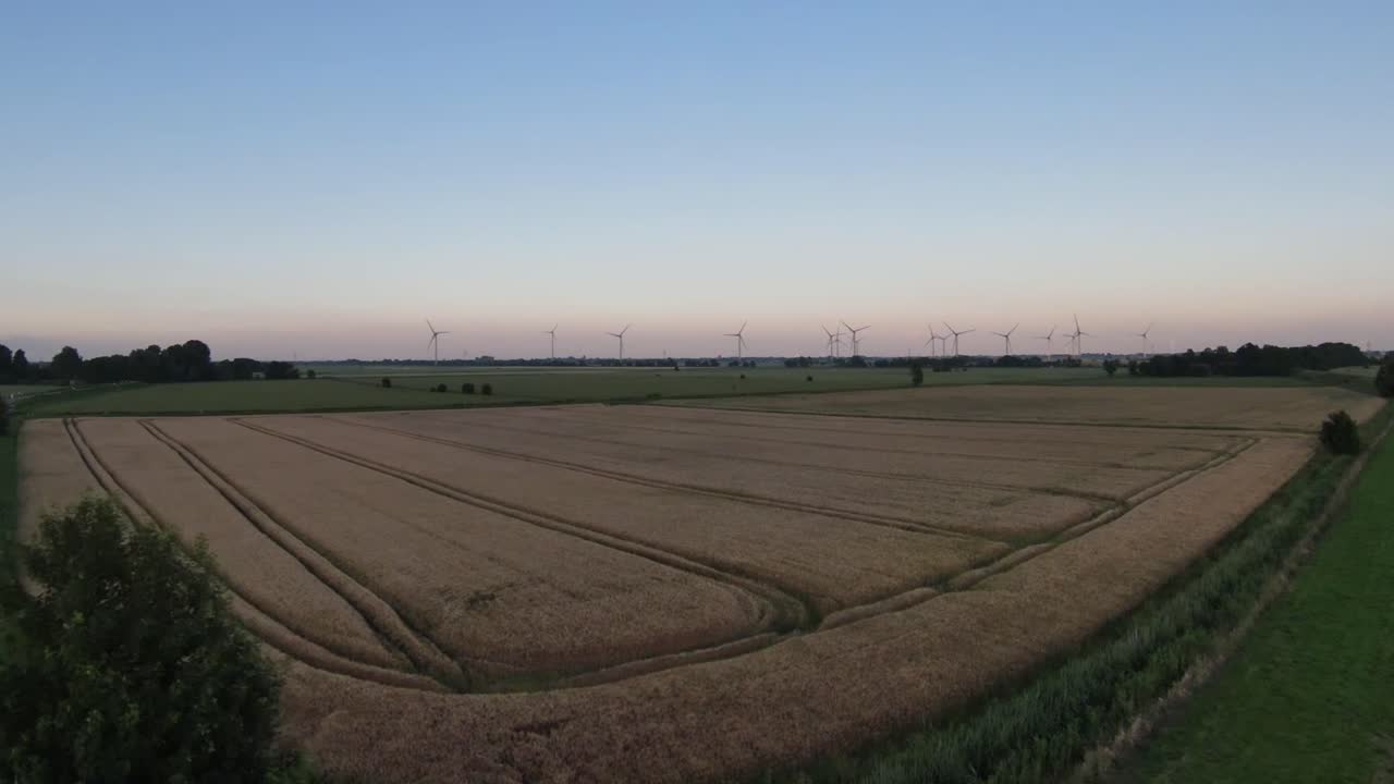 drone shot in the evening over fields with several large white pinwheels