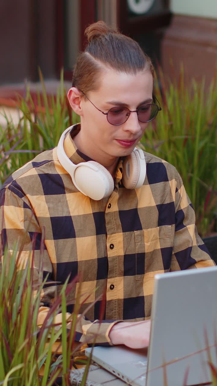 Un giovane turista felice che lavora online un lavoro a distanza un portatile un netbook in una strada della città un ristorante di caffè