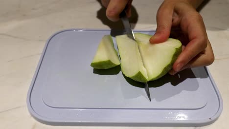 slicing a pear with a knife on a board