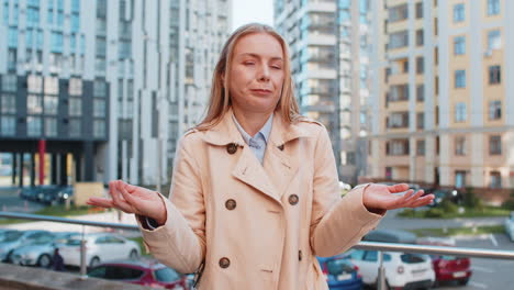 doubtful sad frustrated mature caucasian woman shrugging shoulders dont know answer on city street