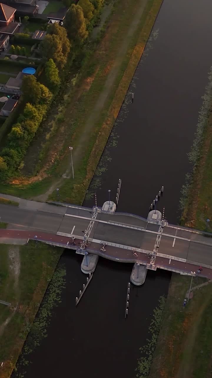Aerial view of a drawbridge over a canal with cyclists at dusk