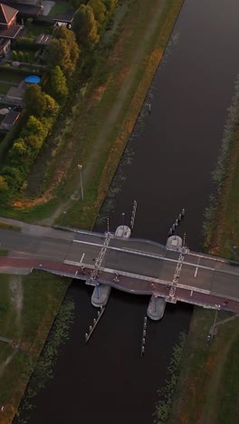 Aerial view of a drawbridge over a canal with cyclists at dusk