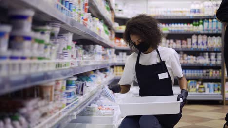 female worker arranging products on shelves in milk department in supermarket, slow motion