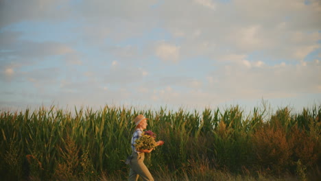 woman farmer harvesting flowers in a cornfield at sunset