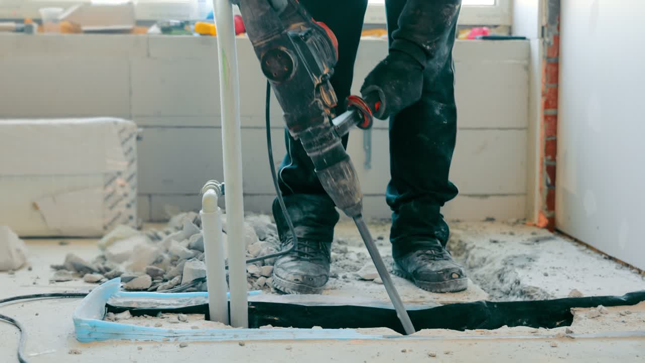 Costruzione e riparazione in una stanza o casa. Utensili elettrici per rompere il rivestimento in cemento. L'operaio rompe il cemento con un martello demolitore.
