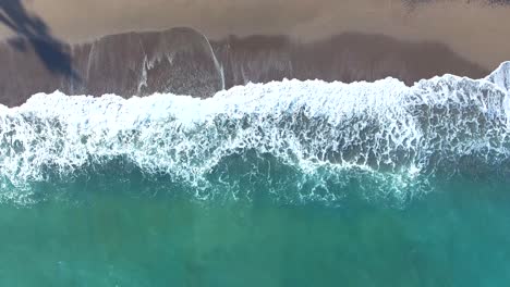 aerial view waves crashing on tropical beach sand