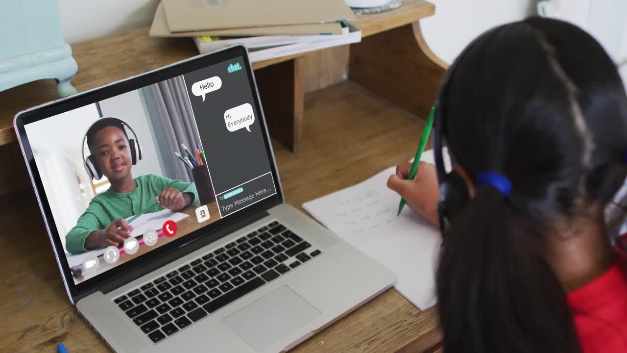 Schoolgirl using laptop for online lesson at home, with her school friend and web chat on screen