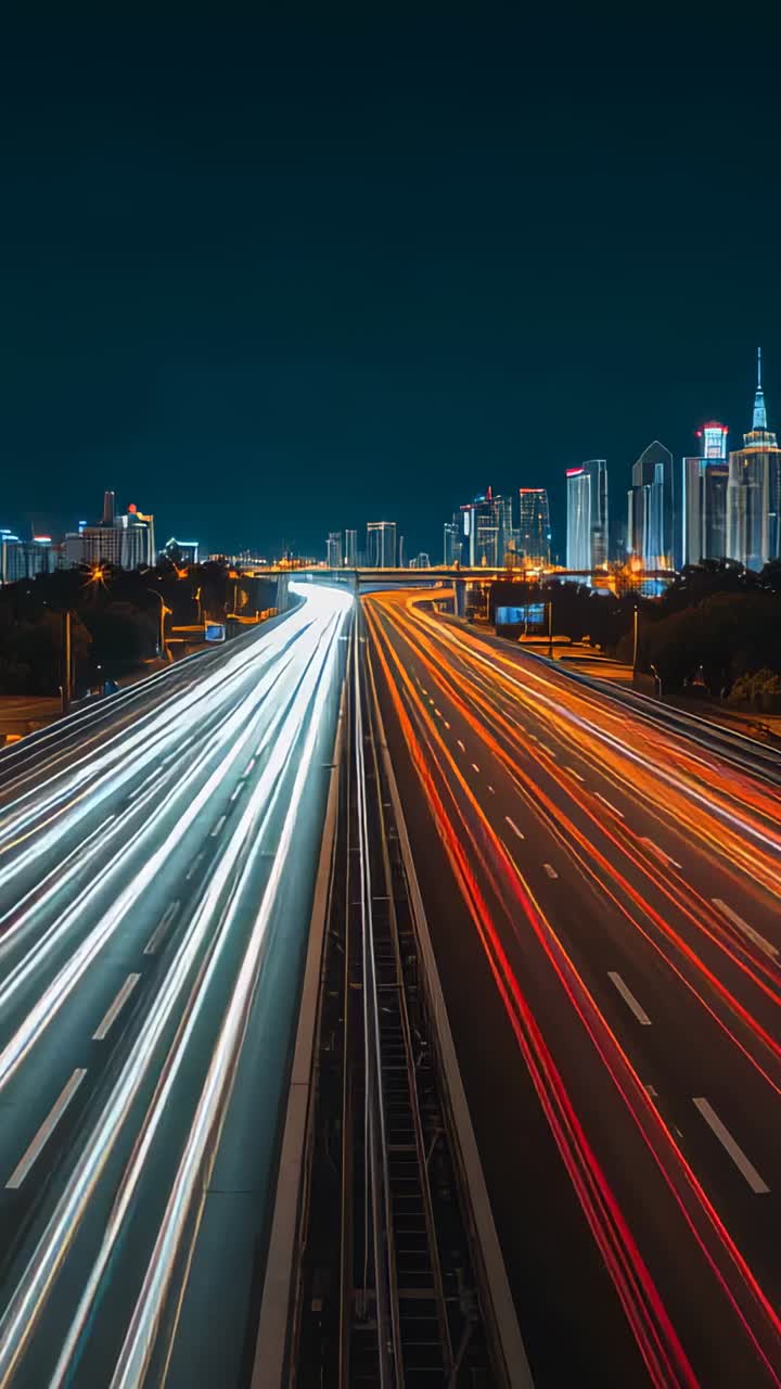 Vertical video: Streaming light trails moving to downtown over bridge at night on multilane highway