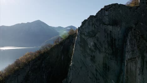 Aufsteigende-Luftaufnahme-Der-Klippenwand,-Die-Den-Malerischen-Iseosee-Und-Die-Küste-Der-Moorbucht-Freigibt