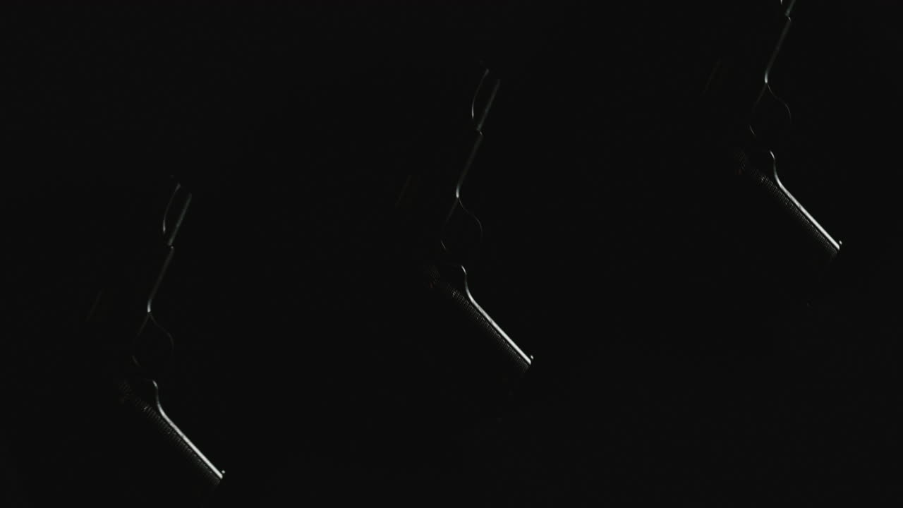 Three pistols on the dark background and in blinking lights are falling in slowmotion