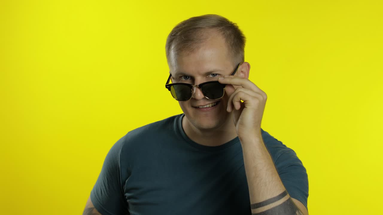 retrato de un joven posando en camiseta. tipo guapo y fresco con gafas de sol mirando a la cámara y guiñando el ojo