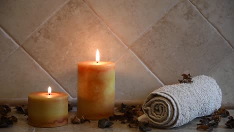 relaxing spa background with candles with flickering flames, some wooden petals and a towel