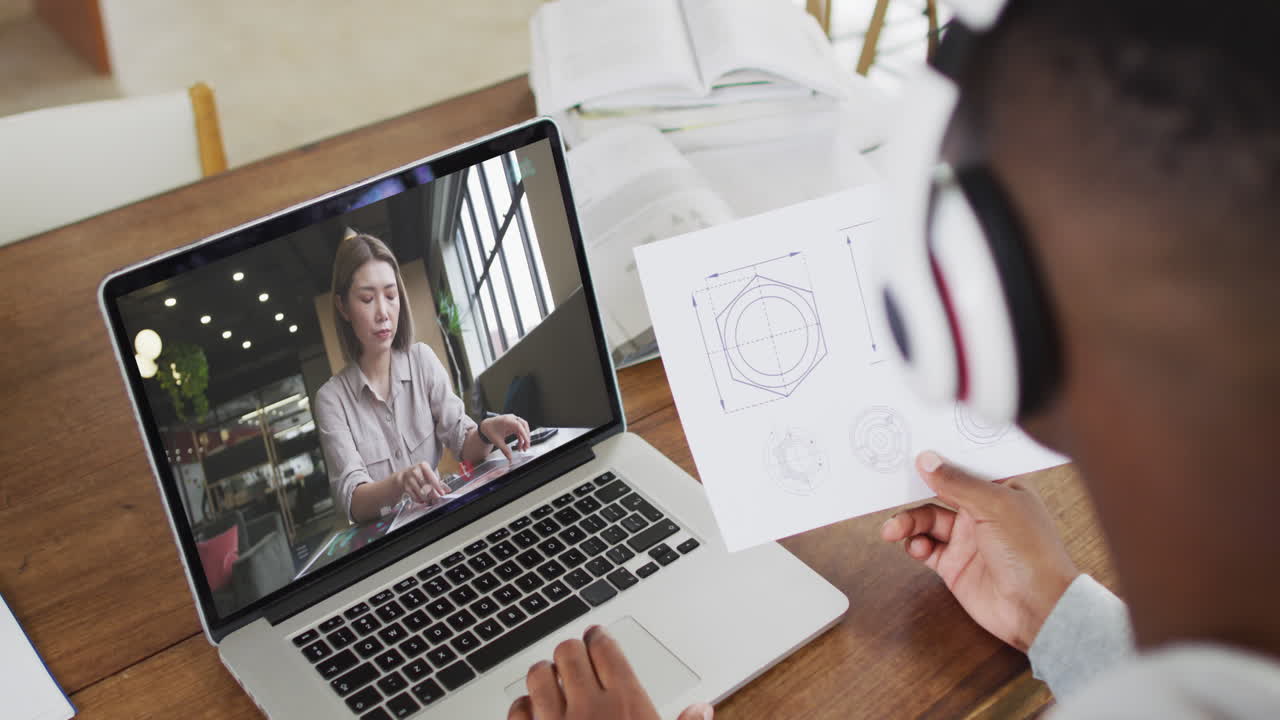 hombre de negocios afroamericano sentado en un escritorio usando una computadora portátil haciendo una videollamada con una colega