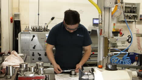 industrial worker measuring with a micrometer in a manufacturing plant