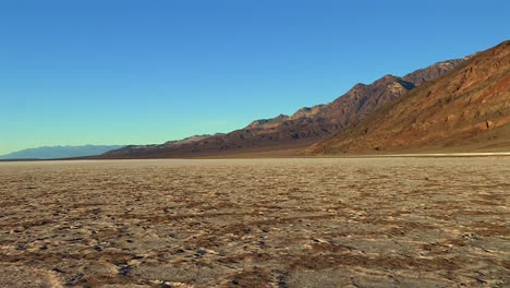 expansive salt flat, jagged mountains and a clear blue sky in death valley national park, california, usa