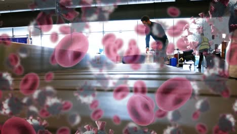 Animation-of-blood-and-macro-Covid-19-cells-floating-over-people-taking-their-baggage-at-airport