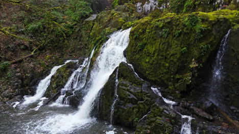 4K-Drohnenaufnahmen,-Seitenansicht-Eines-Wasserfalls-In-Einem-Mit-Moosfelsen-Bedeckten-Wald-Im-Pazifischen-Nordwesten-Amerikas